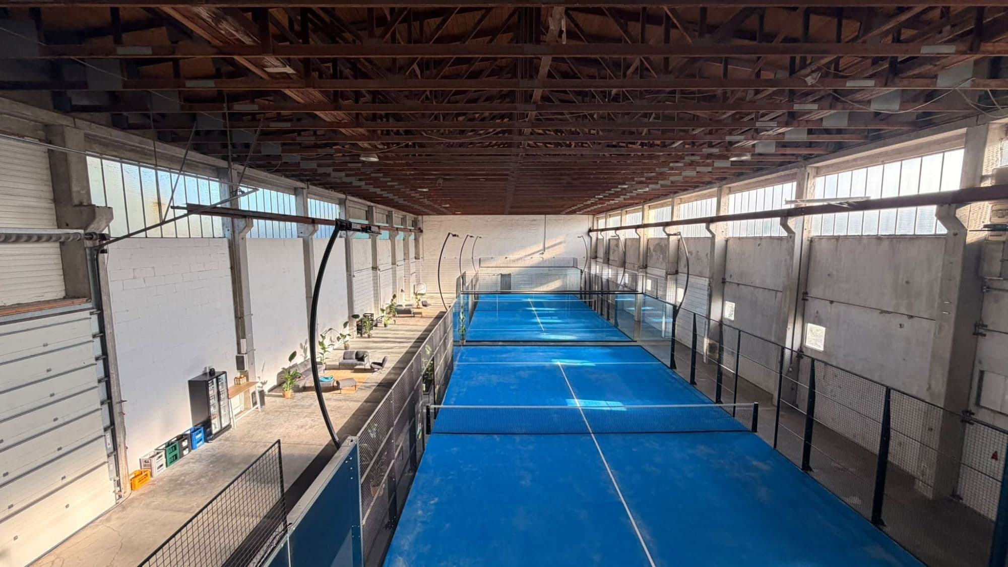 Die zwei Indoor-Padel-Courts von oak padel von oben, daneben die Lounge in der ehemaligen Gewerbehalle in Aichach